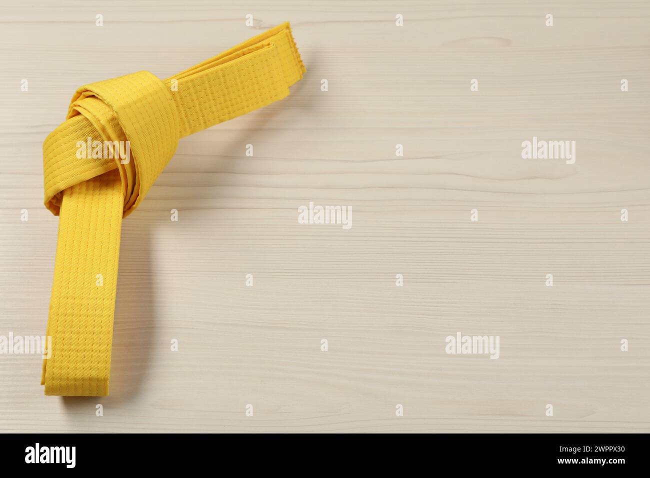 Gelber Karategürtel auf hölzernem Hintergrund, Platz für Text Stockfoto
