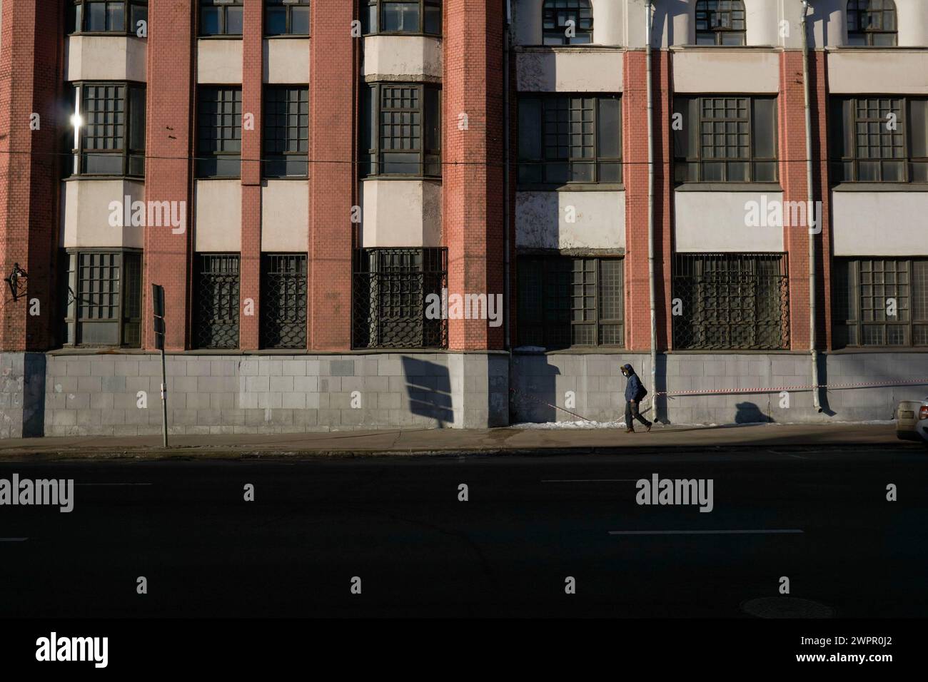 Moskau, Russland. März 2024. Ein einsamer Passant in der Nähe der Fassade eines monumentalen sowjetischen Gebäudes in der Semlyanoy Val Street im frühen Frühjahr Moskau. Die Muskowiter rasen mit ihrem Geschäft, während sich das Leben um sie herum verändert: Alte Gebäude verfallen, neue menschliche Siedlungen werden von Bauunternehmern gebaut, Menschen, die Lebensmittel liefern, und Taxis beeilen sich, Aufträge zu erfüllen. Quelle: SOPA Images Limited/Alamy Live News Stockfoto