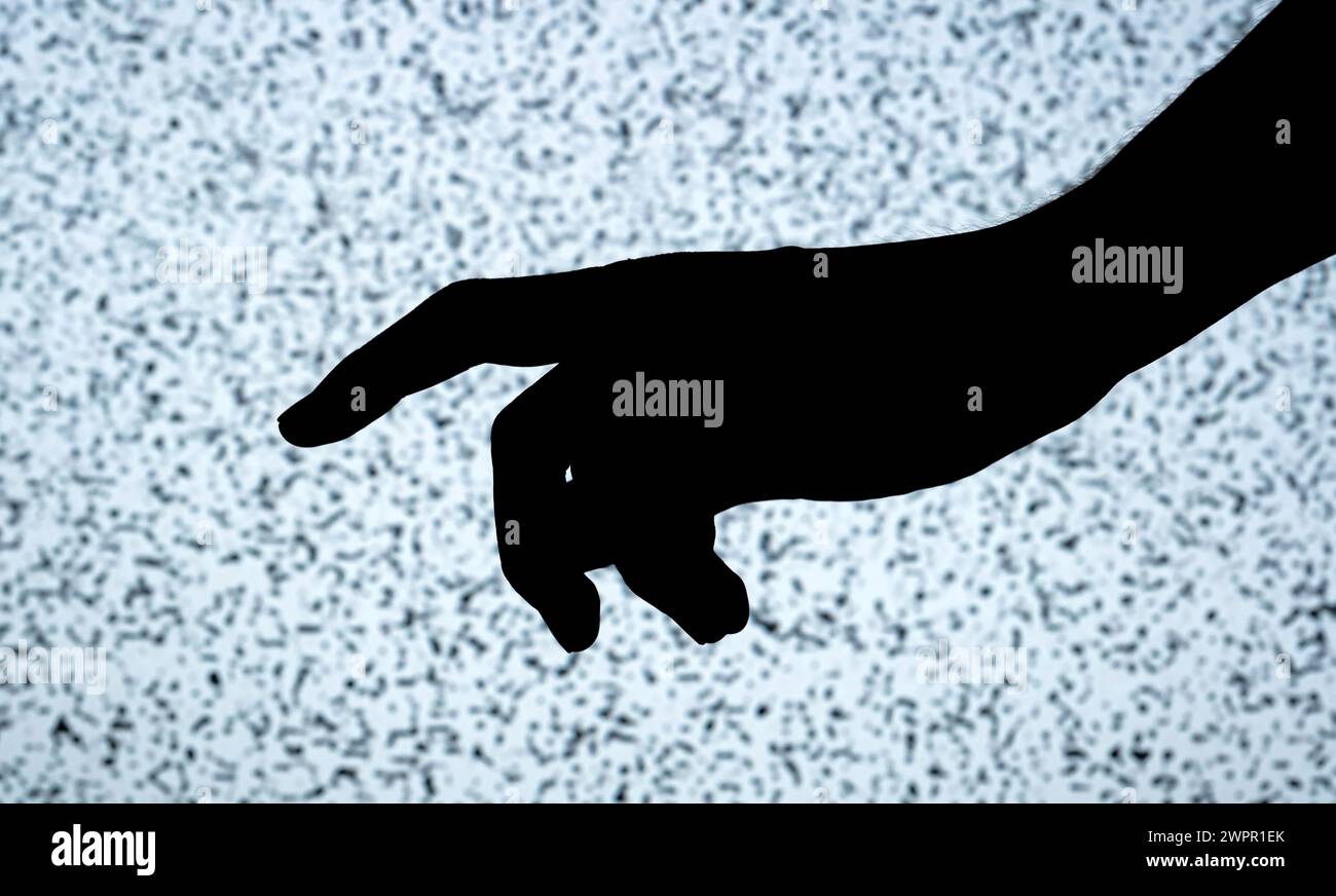 Dunkle Umrisse einer Person mit gestreckter Hand und Zeigefinger hoher Kontrast zum hellen, strukturierten Hintergrund eines Fernsehbildschirms mit weißem noi Stockfoto