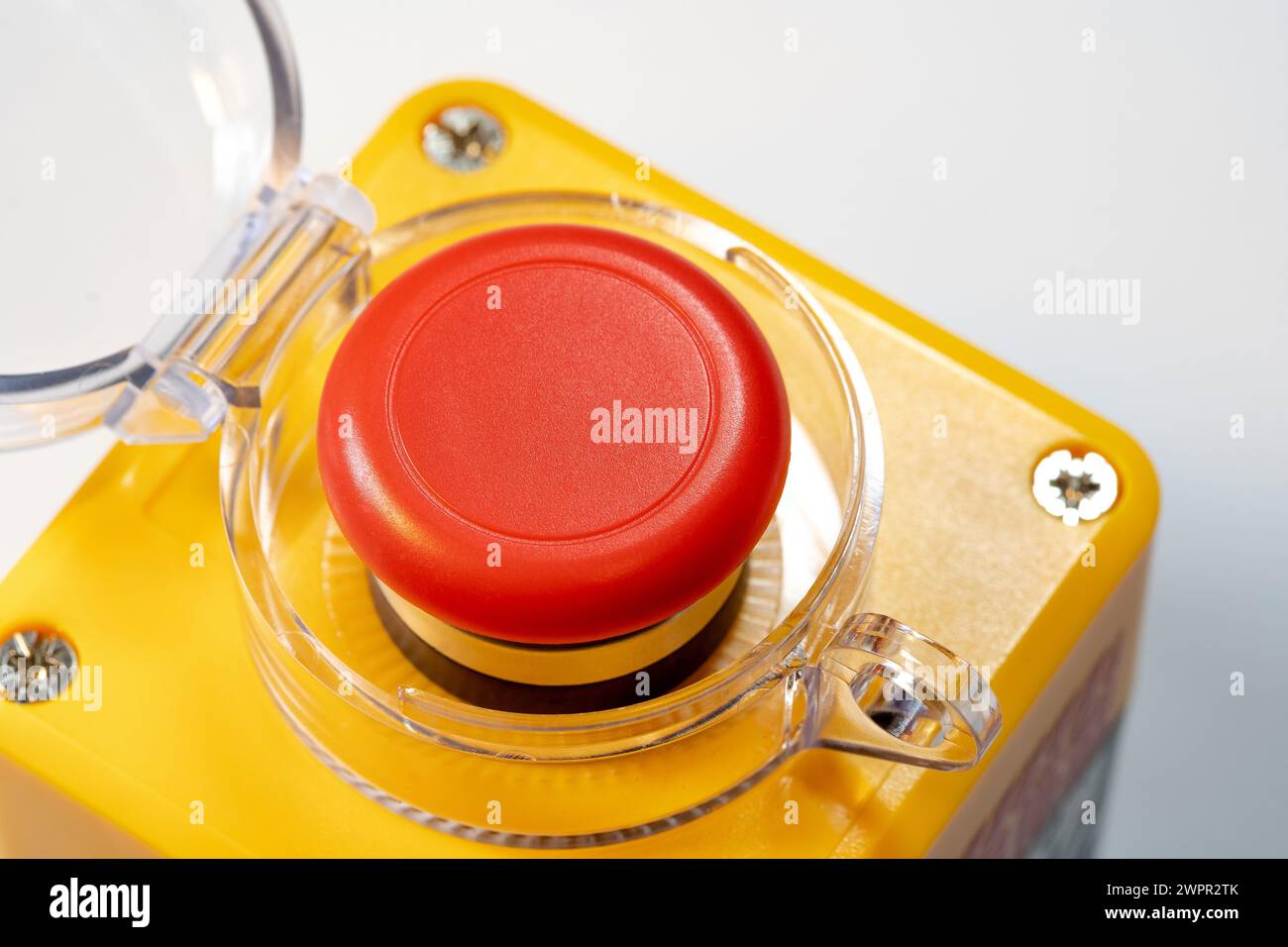Detaillierte Nahaufnahme eines roten Not-aus-Schalters für Industriemaschinen, eines roten gelben Panikschalters mit geöffneter Abdeckung. Hohe Beanspruchung Stockfoto