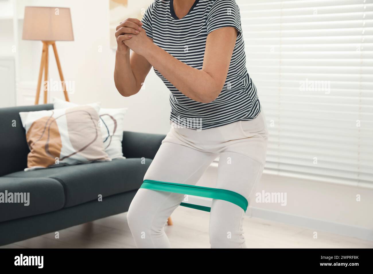 Ältere Frau, die Squats mit Fitness-Elastikband zu Hause macht, Nahaufnahme Stockfoto