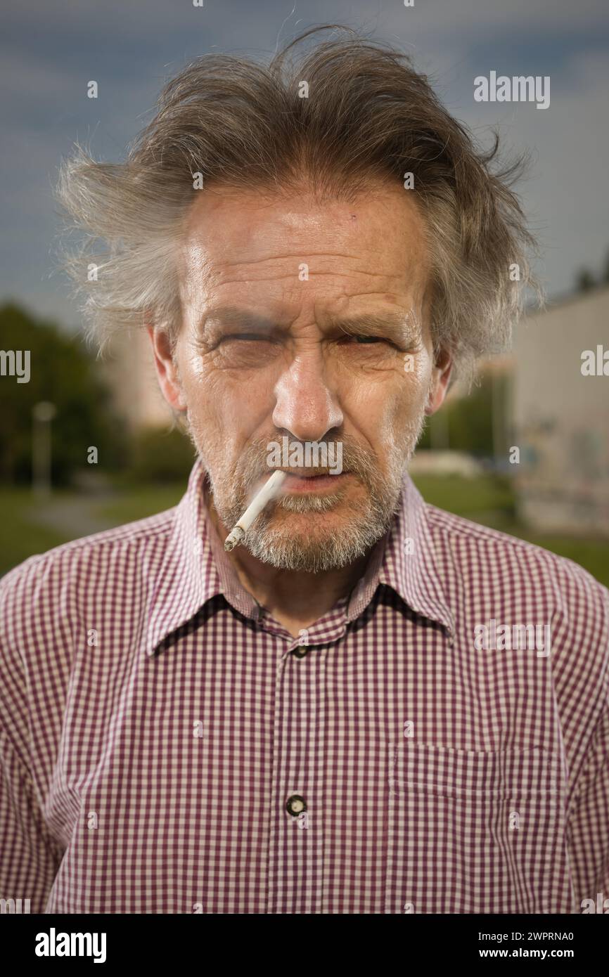 Ein alter Mann, der Zigaretten im Stadtpark raucht, in letzter Zeit am Tag Stockfoto