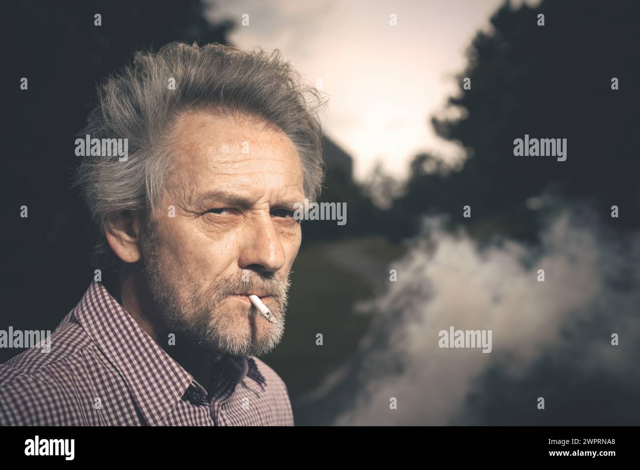 Ein alter Mann, der Zigaretten im Stadtpark raucht, in letzter Zeit am Tag Stockfoto