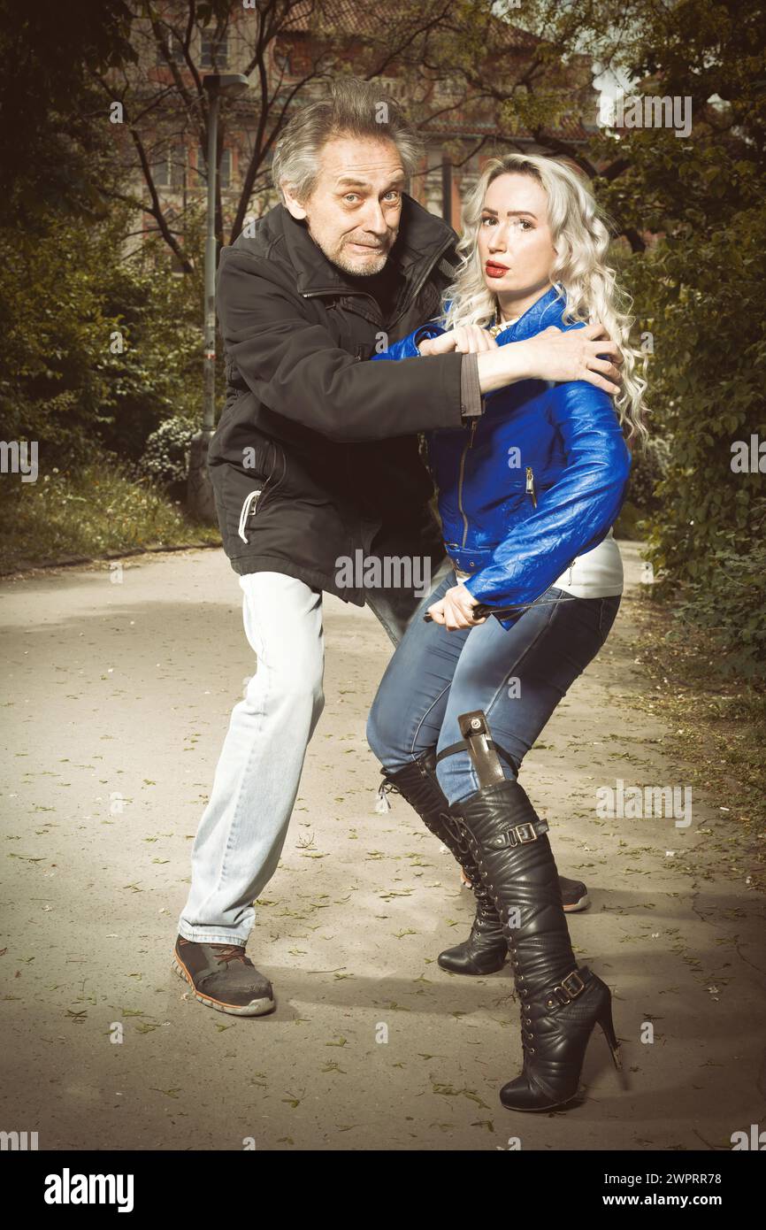 Hübsche junge Frau, die von einem älteren Mann im Park verfolgt und angegriffen wird Stockfoto