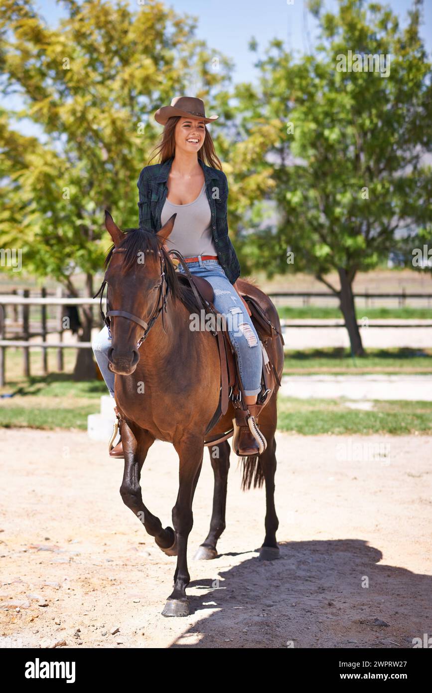 Cowgirl, Frau und Lächeln mit Pferd für Reiten auf Ranch, Farm oder Natur mit Baum im Freien am Wochenende. Glückliche Person und aufgeregt mit Tier auf Sand drin Stockfoto