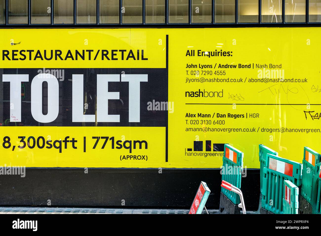 Soho, London UK, 08. März 2024, großer gelber Shop oder Store to Let Sign mit No People und grünen Sicherheitsbarrieren Stockfoto