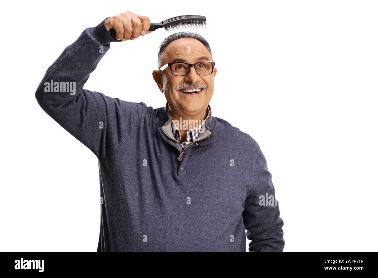 Reifer Mann, der eine Haarbürste über dem Kopf hält, isoliert auf weißem Hintergrund, Haarausfall-Konzept Stockfoto
