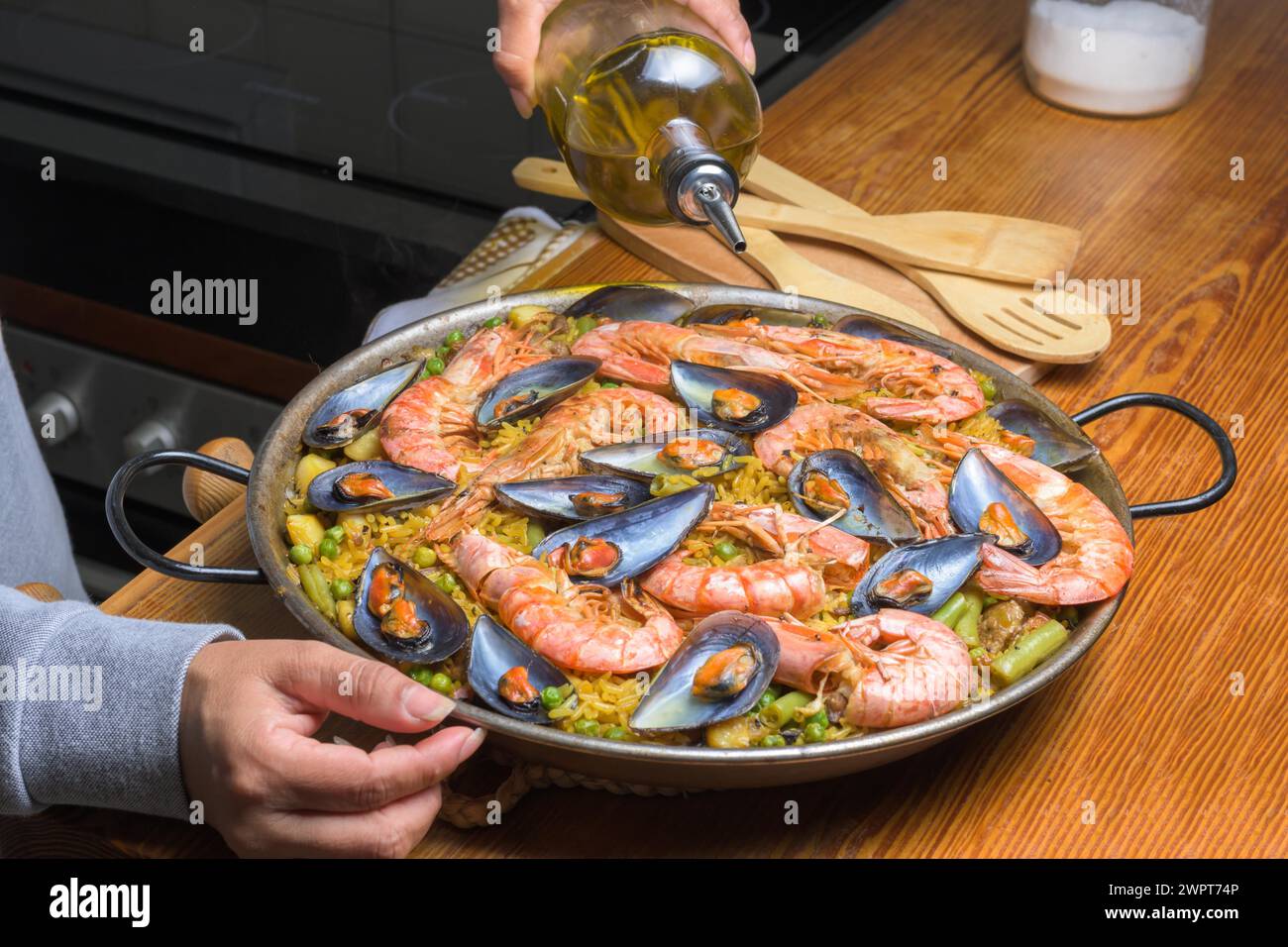 Füllen Sie Olivenöl in eine Paella mit Meeresfrüchten, um die Aromen dieses klassischen spanischen Gerichts zu verstärken, typisch spanische Küche, Mallorca, Balearen, Spanien Stockfoto