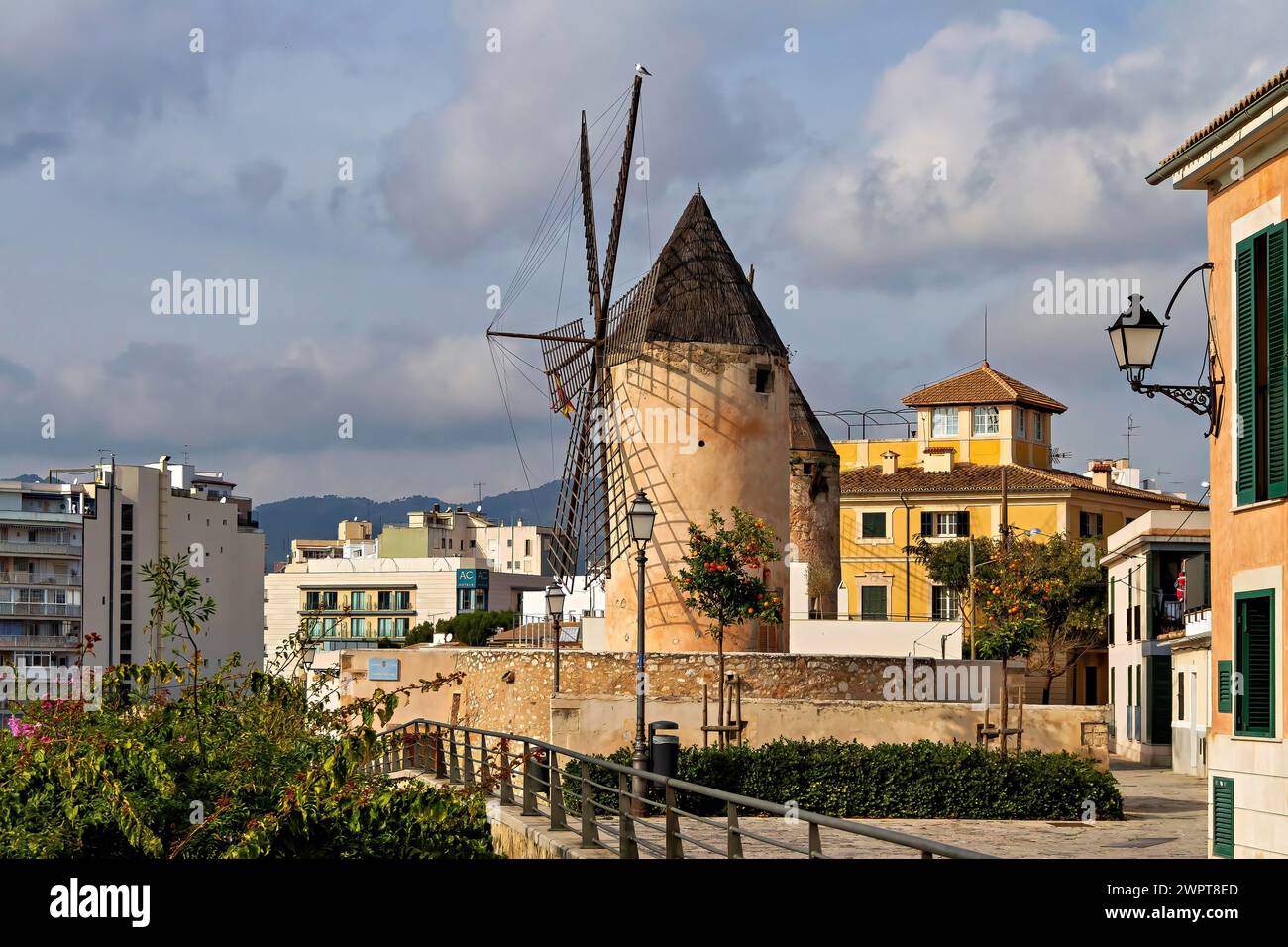 Traditionelle Windmühle mit alten Gebäuden unter blauem Himmel mit verstreuten Wolken, Palma de Mallorca Stockfoto
