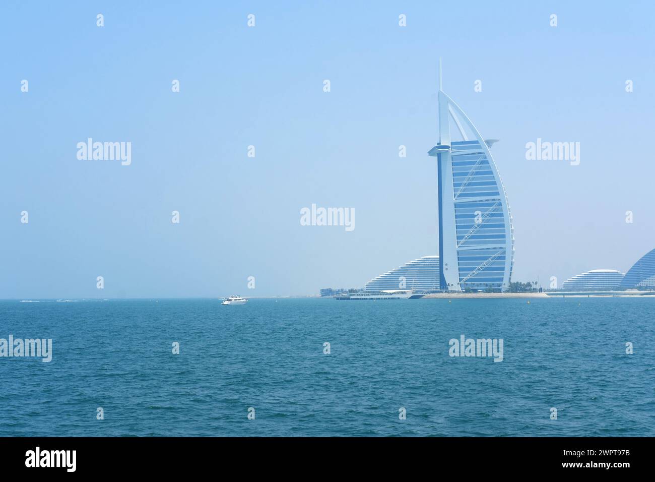 Ein ruhiger Blick auf den Burj Al Arab und das ruhige Meer, mit Freizeitbooten, die auf den Gewässern von Dubai fahren. Dubai, VAE - 15. August 2023 Stockfoto