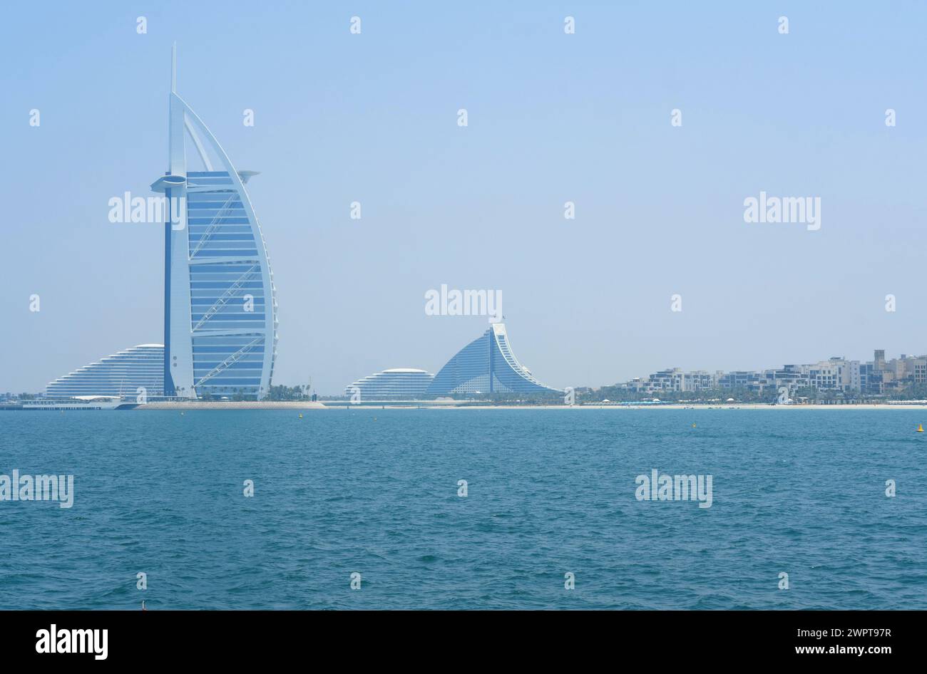 Das legendäre Burj Al Arab steht neben luxuriösen Strandresorts an einem klaren Tag in Dubais Küstenlandschaft hoch. Dubai, VAE - 15. August 2023 Stockfoto