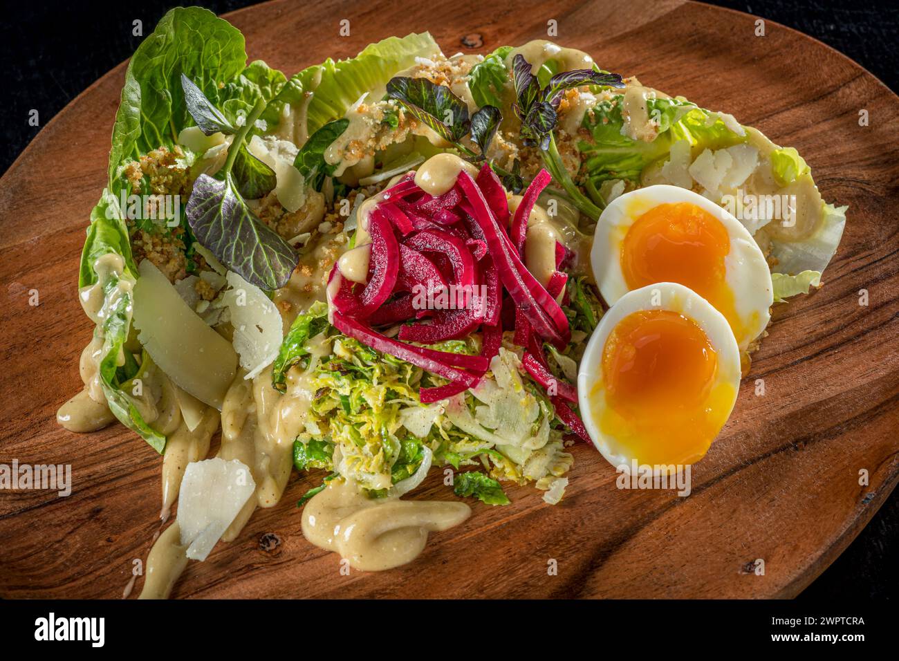 Salat auf Holzteller mit weich gekochtem Ei Stockfoto