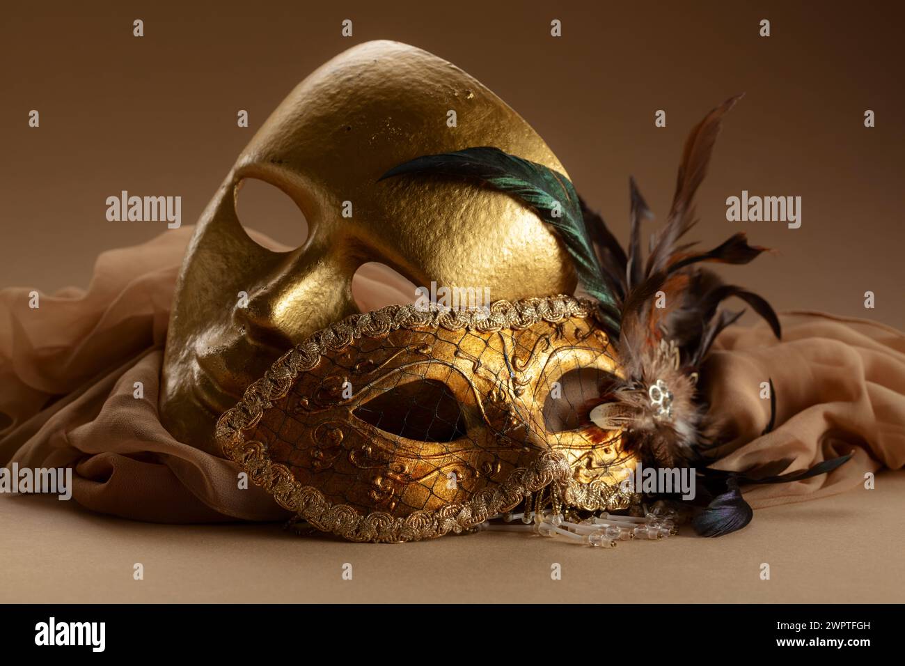 Goldene venezianische Karnevalsmasken. Vintage-Masken auf beigefarbenem Hintergrund. Stockfoto
