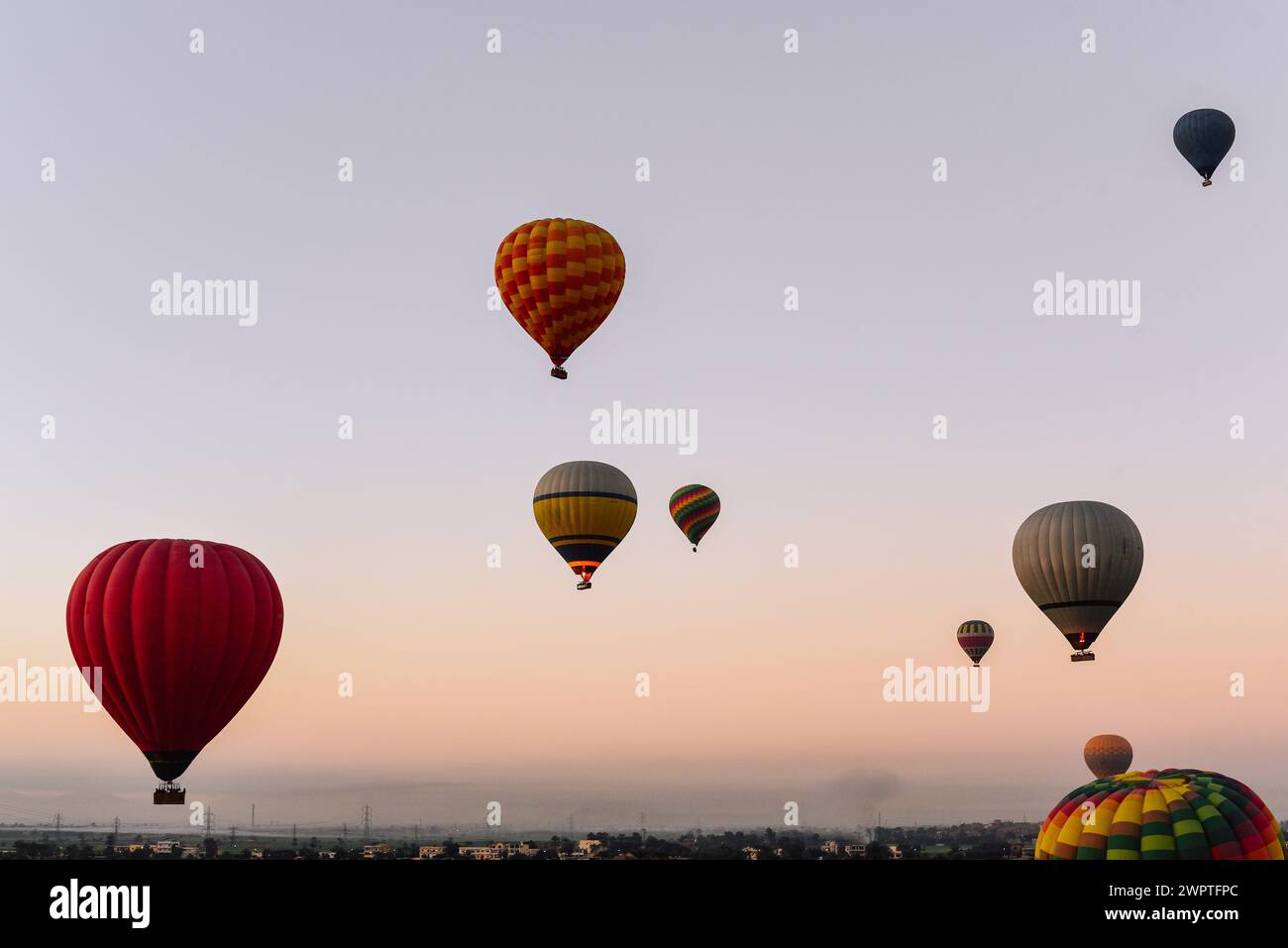 Weite Sicht auf Dutzende von Heißluftballons, die um Luxor, Ägypten, fliegen Stockfoto