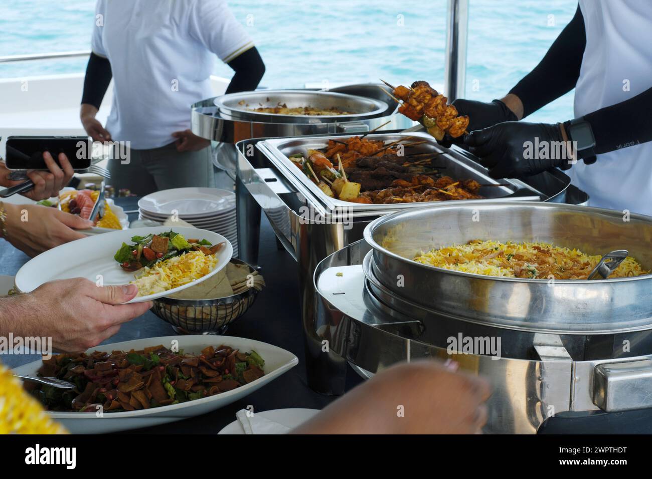 Gäste erhalten ein Gourmet-Mittagsbuffet auf einer Yacht mit Meeresblick in Dubai Stockfoto