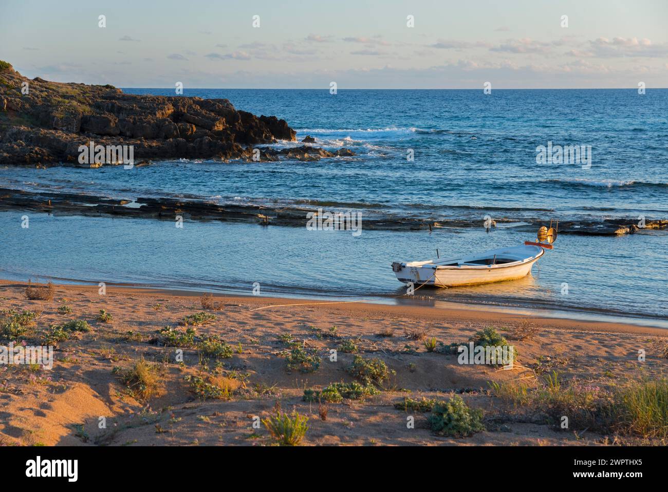 Ruhige Szene eines einzelnen Bootes an der Küste mit Felsen im sanften Abendlicht, Finikounda, Pylos-Nestor, Messinia, Peloponnes, Griechenland Stockfoto