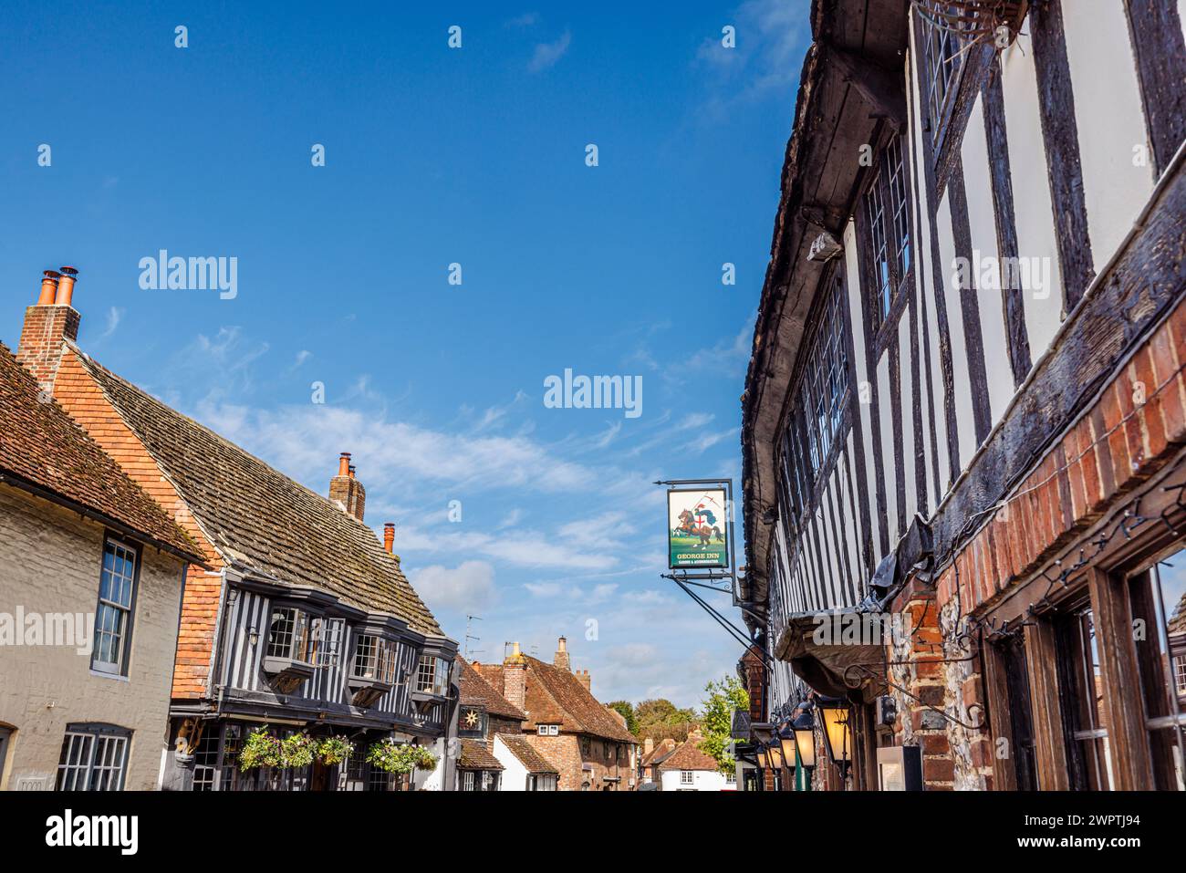 Das schwarz-weiße, aus Fachwerk gefertigte George Inn and Pub Schild in der High Street, Alfriston, einem hübschen historischen Dorf im Wealden District in East Sussex Stockfoto