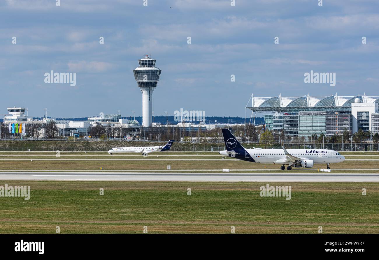 Ein Airbus A320-214 von Lufthansa rollt nach der Landung auf der Südbahn des Flughafens München zum Terminal. Registrierung D-AIUF. Dahinter rollt ein C Stockfoto