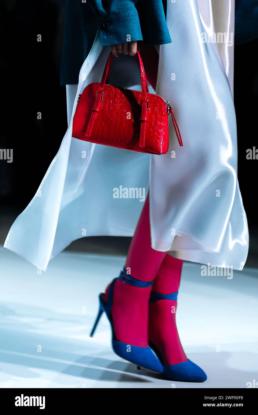 Modische Details eines weißen Seidenkleides und einer roten Handtasche in der Hand einer Frau. Elegante Kleidung und Accessoires Stockfoto