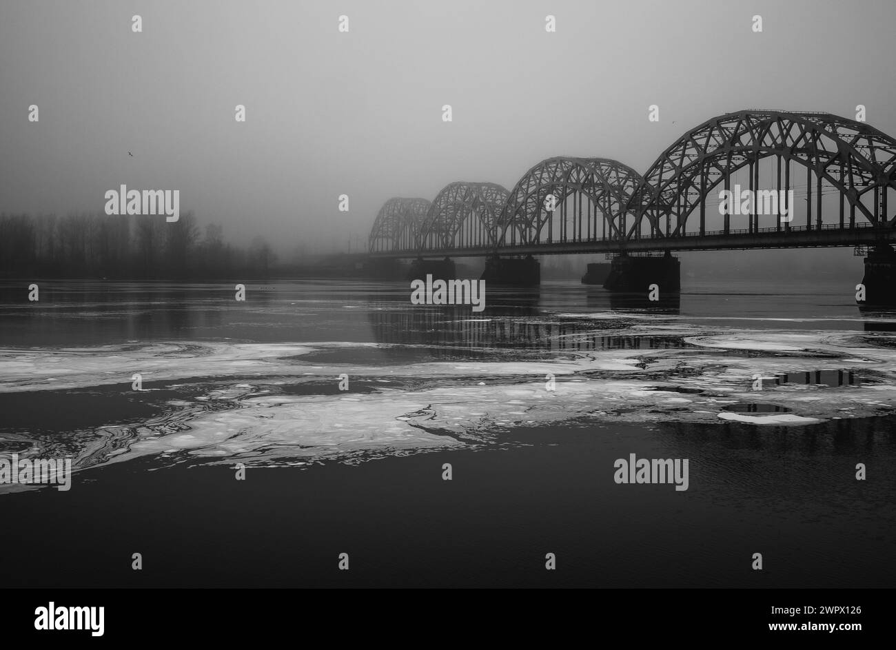Rigaer Eisenbahnbrücke über den nebligen Daugava Fluss schwarz-weiß 28.02.2024 Stockfoto
