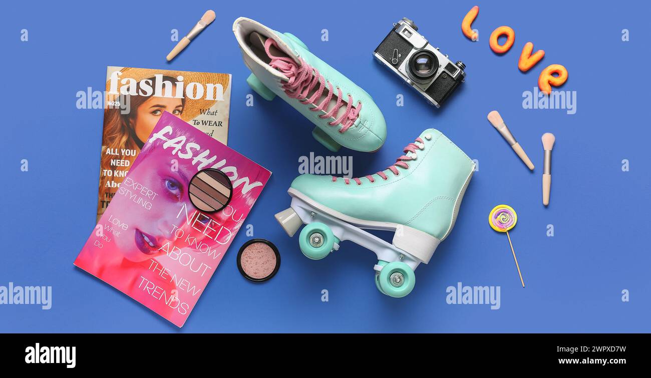 Komposition mit Paar Vintage Rollschuhe, Fotokamera, Zeitschriften und Make-up Kosmetik auf blauem Hintergrund Stockfoto