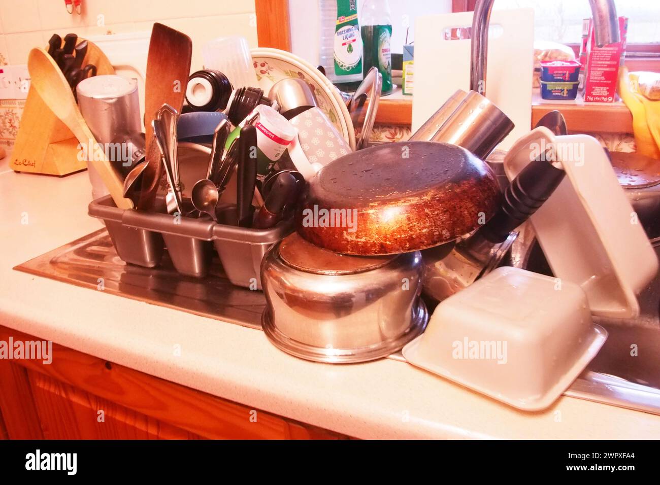 Ein großer Haufen Geschirrspülung auf einem Abfluss mit Töpfen, Pfannen und Utensilien Stockfoto