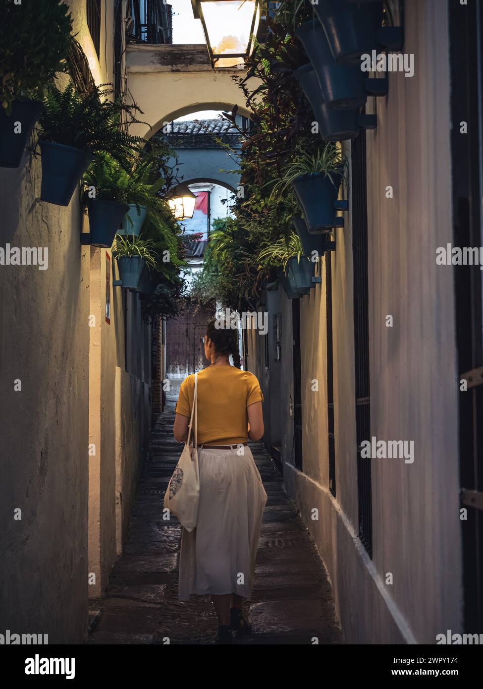 Junge schöne Frau, die abends die Calleja de las Flores Straße entlang geht, Cordoba, Andalusien, Spanien Stockfoto