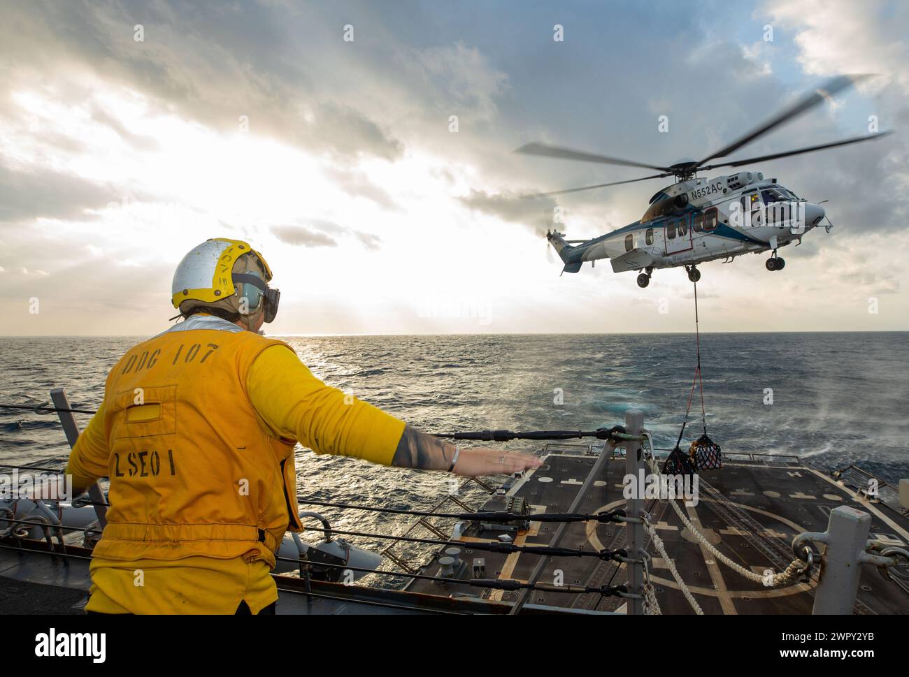 240118-N-BT677-1060 RED SEA (18. Januar 2024) Ein Boatswain's Mate, der dem Arleigh-Burke-Klasse USS Gravely (DDG 107) zugeordnet ist, signalisiert einen H225 Super Puma Hubschrauber während eines Wiederauffüllens auf See mit dem Trockenfrachtschiff USNS Alan Shepard (T-AKE 3) der Lewis-Klasse im Roten Meer, 18. Januar. Gravely wird in das Einsatzgebiet der 5. US-Flotte eingesetzt, um die Sicherheit und Stabilität im Nahen Osten zu gewährleisten. (Offizielles Foto der US Navy) Stockfoto