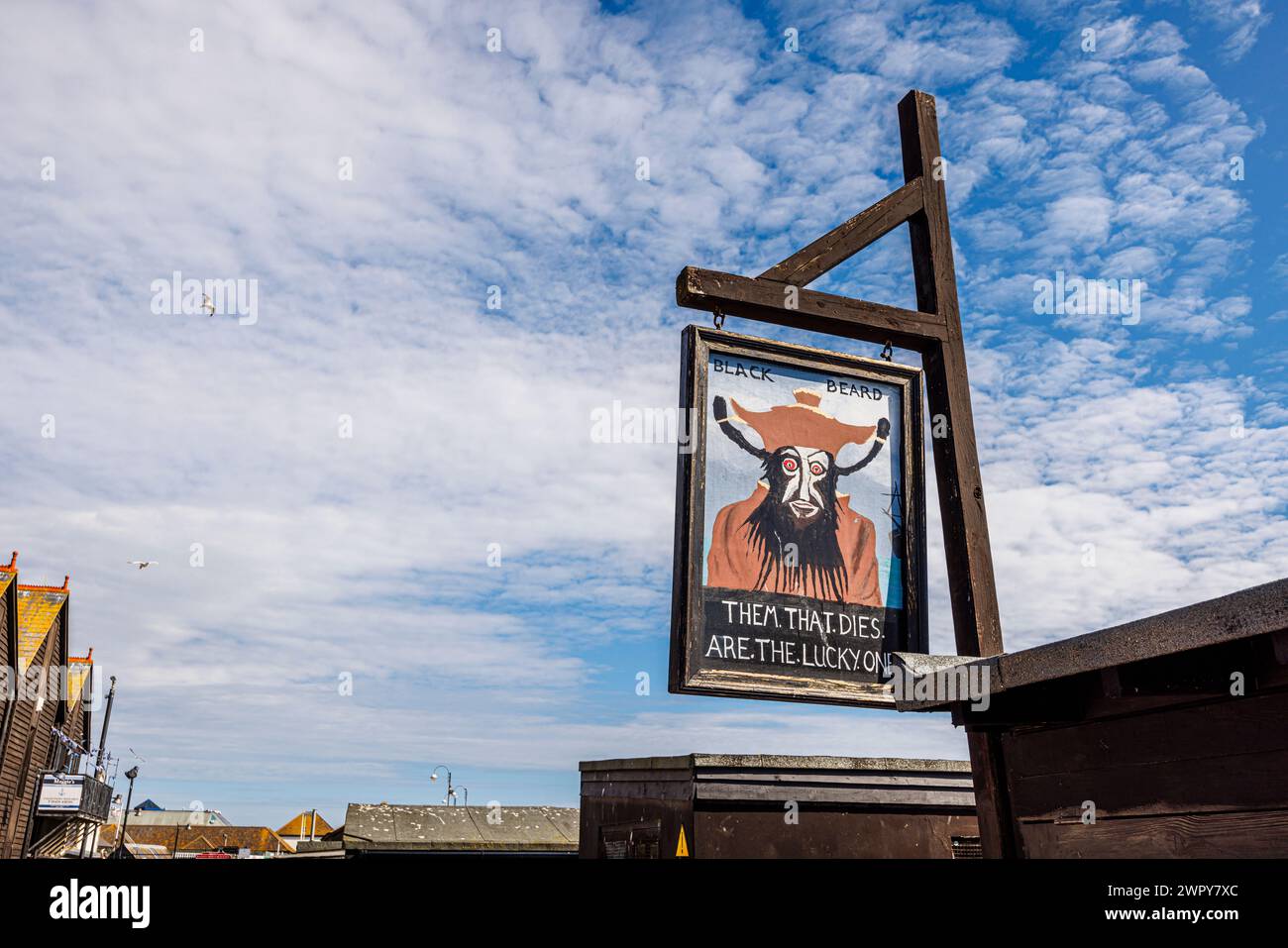 Amüsantes hölzernes Schild mit Blackbeard und „Them that stirbt are the Lucky Ones“ im Stade in der Altstadt von Hastings, East Sussex, England Stockfoto