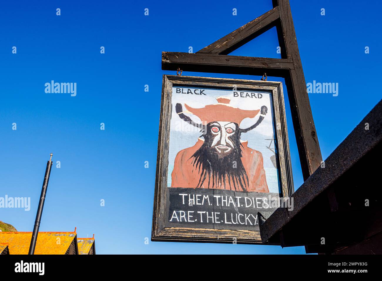 Amüsantes hölzernes Schild mit Blackbeard und „Them that stirbt are the Lucky Ones“ im Stade in der Altstadt von Hastings, East Sussex, England Stockfoto
