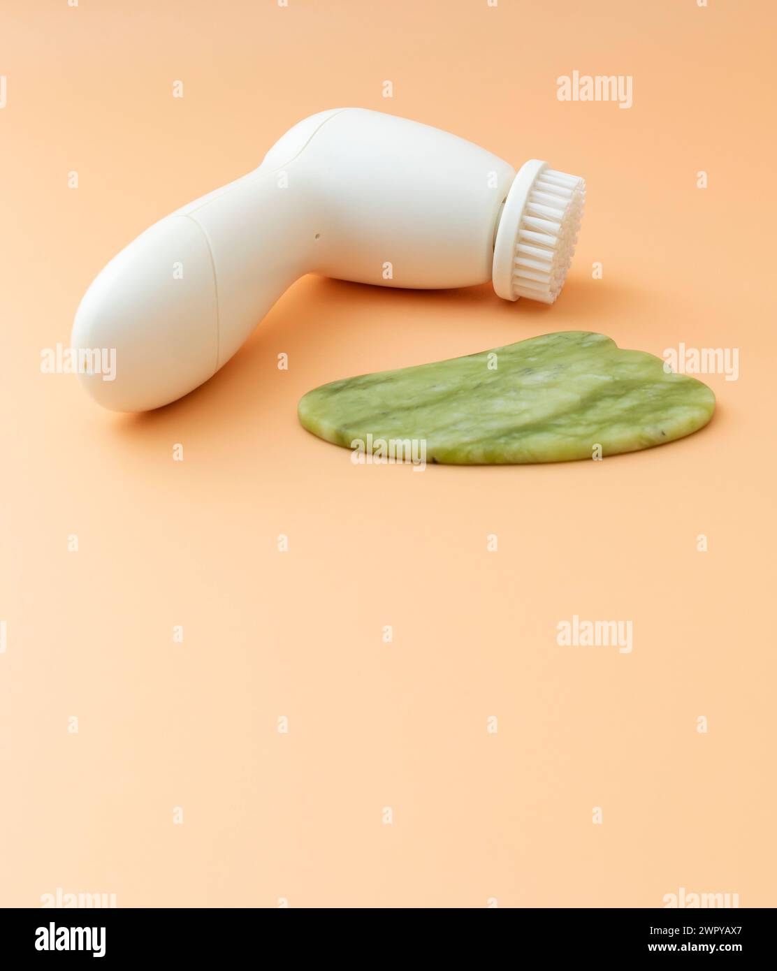 Flatly Mockup Hautpflegeprodukte. Gesichtswerkzeug Gua Sha, Anti-Aging, Gesichtsreinigungsbürste auf beigem Hintergrund. Gerät Für Hautschönheit, Kopierraum Für Text Stockfoto