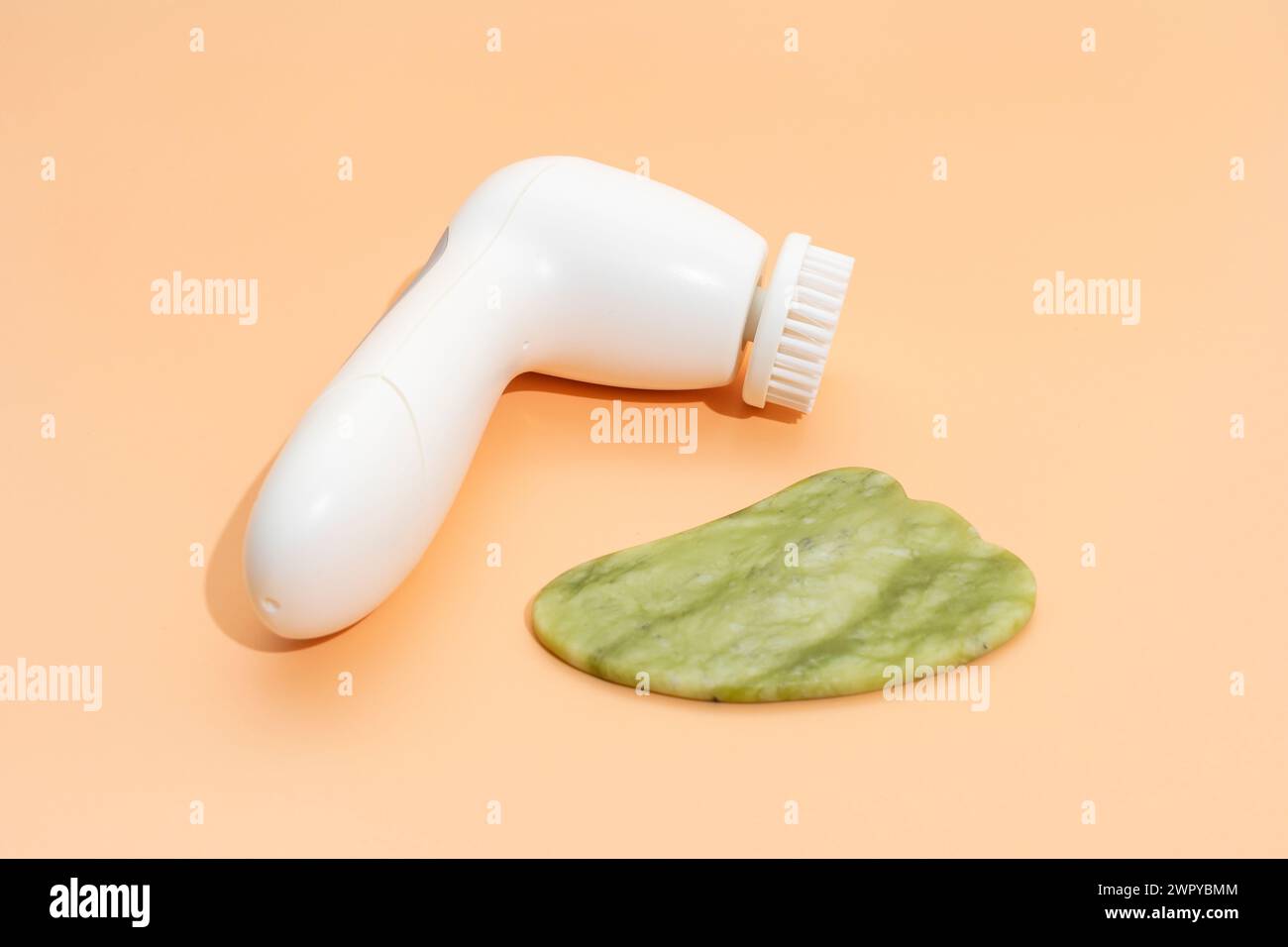 Closeup Hautpflegeprodukte. Gesichtswerkzeug Gua Sha, Anti-Aging, Gesichtsreinigungsbürste auf beigem Hintergrund. Gerät Zur Hautpflege, Horizontale Ebene. Niemand. Stockfoto