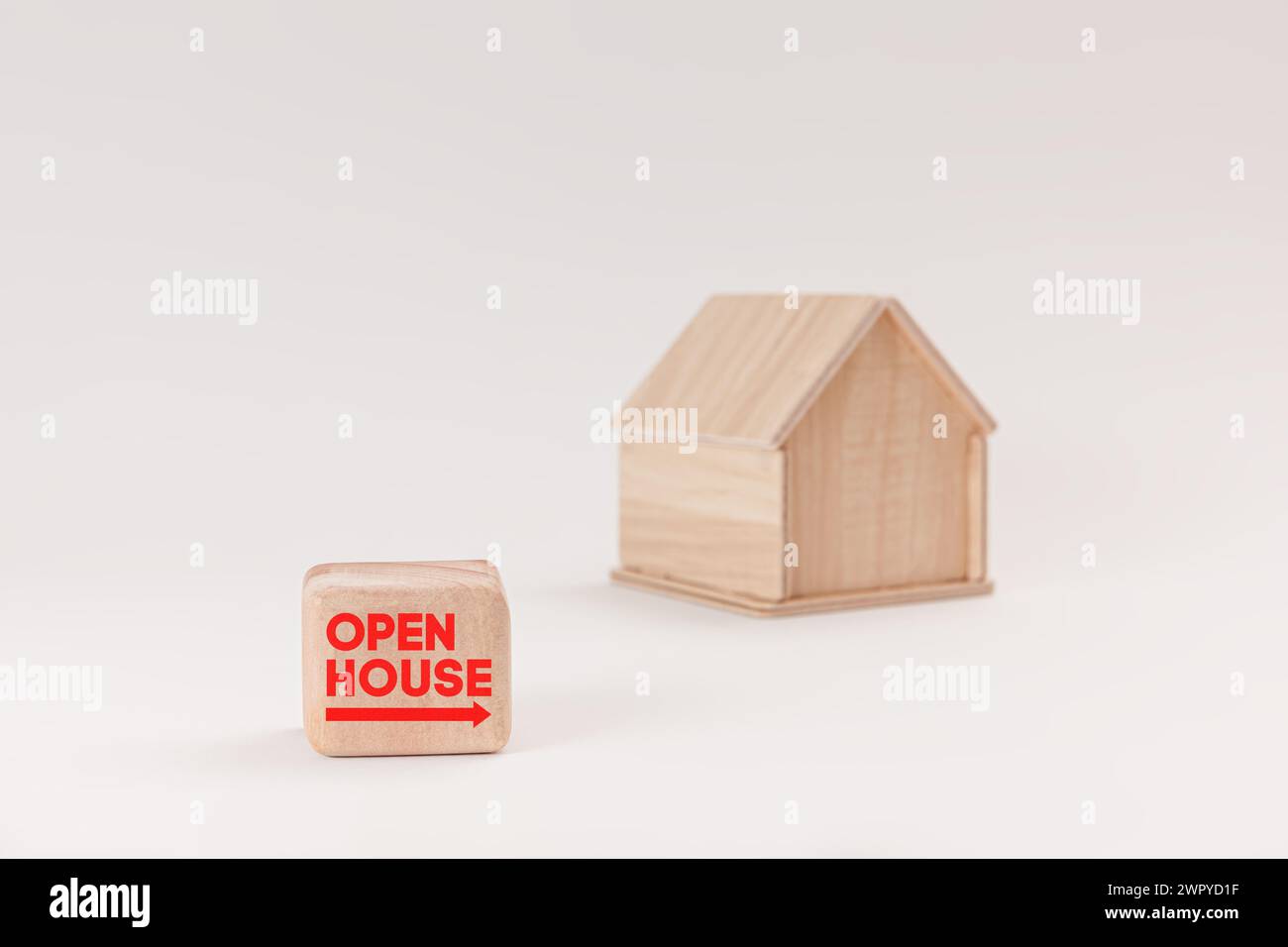 Vereinfachtes hölzernes Hausmodell isoliert auf hellgrünem Hintergrund, mit Text Open House auf dem Schild. Stockfoto