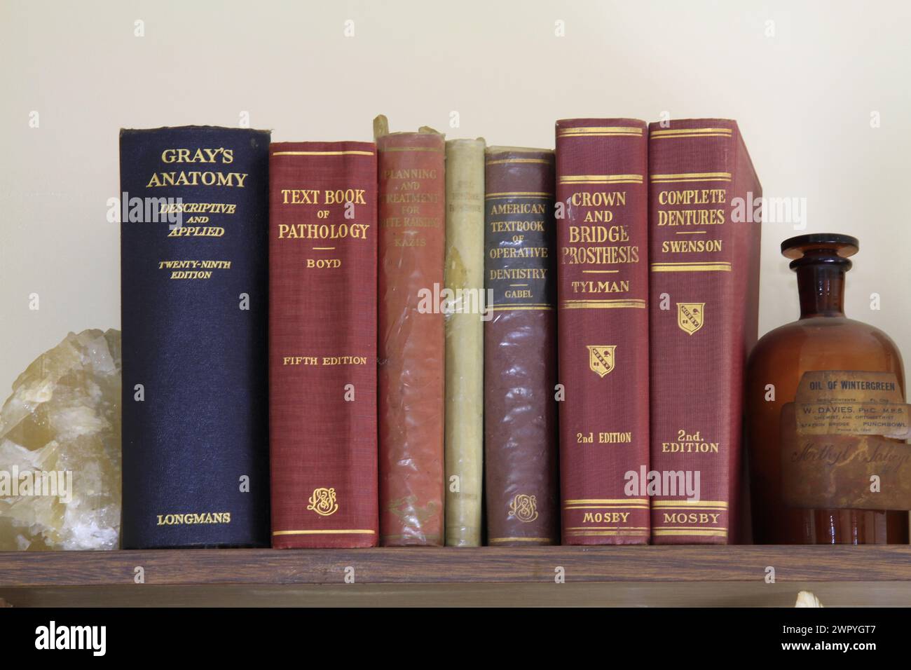 Historische medizinische und zahnärztliche Lehrbücher auf einem Regal mit einer alten Flasche chemischer Reagenzien. Stockfoto