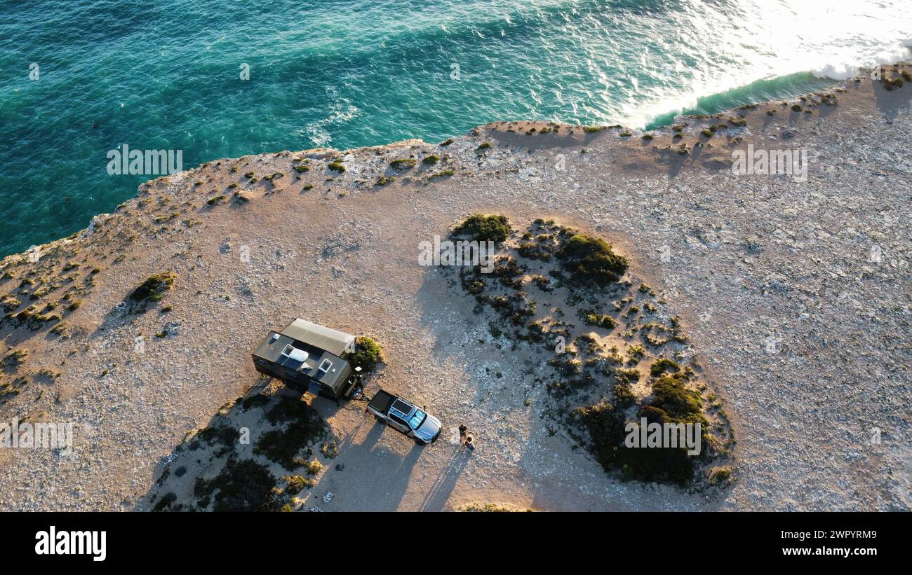 Ein Caravan- und Auto-Campingplatz auf einer Klippe mit Blick auf die klaren blauen Wellen des Ozeans, die Sonnenlicht reflektieren Stockfoto