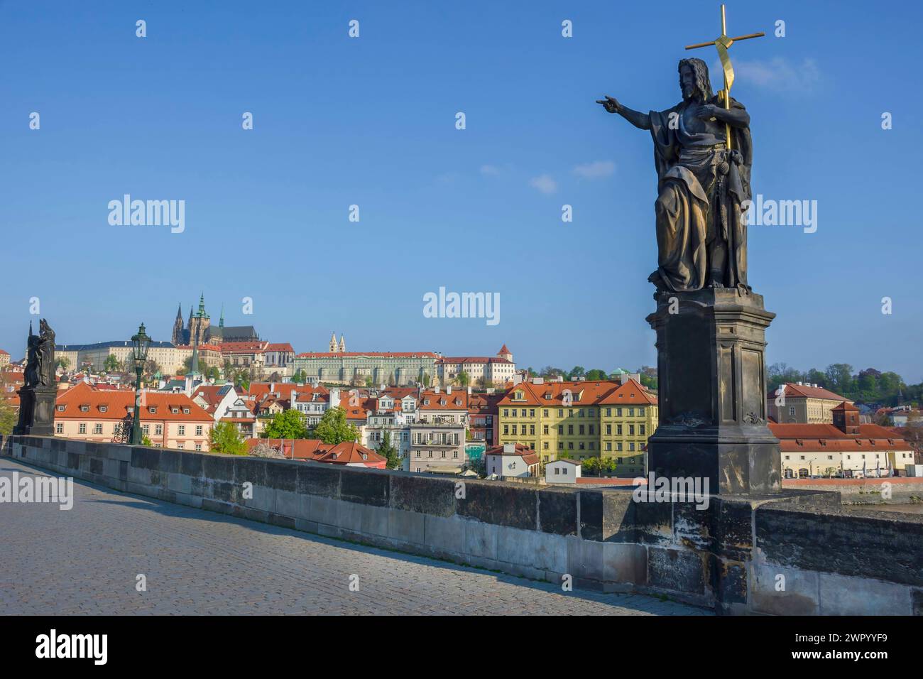 Statue von St. Johannes der Täufer auf der Karlsbrücke, mit Hradcany Castle und St. Vitusdom im Hintergrund, in Prag, Tschechien, sonnig Stockfoto