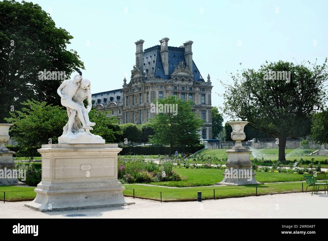 Eine Promenade zwischen Skulpturen, Blumenbeeten und grünen Stühlen in den Tuilerien Jardin. Palais Royal - Musée du Louvre als Kulisse. Paris, Frankreich Stockfoto