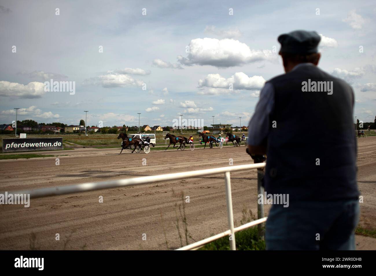 Karlshorst, Trabrennen DEU, Deutschland, Berlin, 30.07.2023 Zuschauer verfolgen das Rennen der Pferde und Fahrer im Sulky am Renntag auf der Trabrennbahn Karlshorst im Pferdesportpark an der Treskowallee im Bezirk Lichtenberg in Berlin Deutschland . Die Traditionelle Pferderennbahn im Trabsport verstroemt aufgrund des alten Erhaltungszustandes bis heute den sproeden Charme der ehemaligen DDR und wird im Gegensatz zu den Besuchern im Galoppsport eher von Rentner und Wettbegeisterten besuchen. de: Zuschauer verfolgen das Rennen der Pferde und Fahrer im Sulky am Tag des Rennens auf t Stockfoto