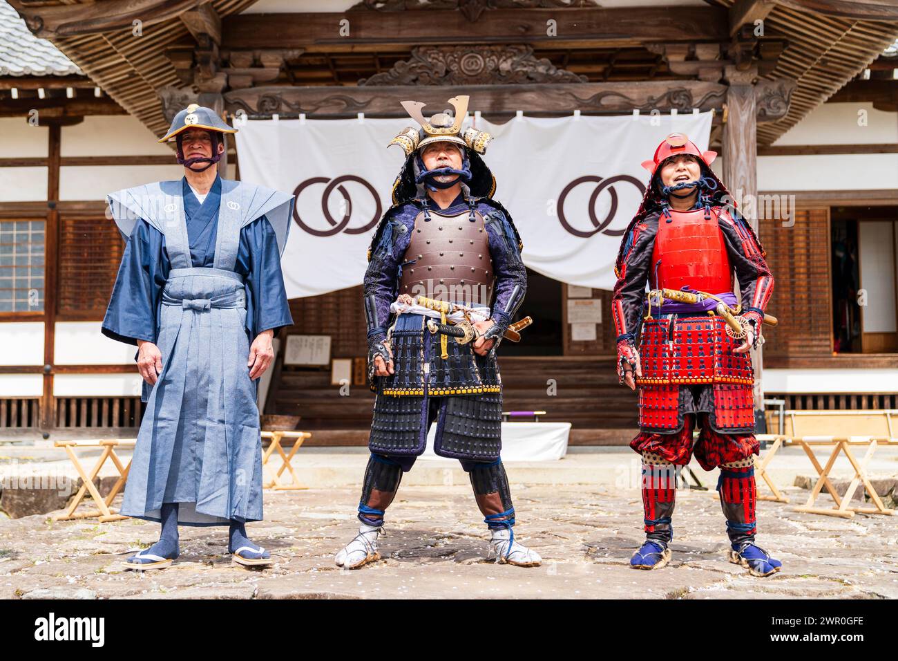 Drei japanische Männer in Samurai-Rüstung posieren für ein Foto vor dem Eingang des Honmaru-Palastes auf der Burg Tatsuno in Japan. Stockfoto