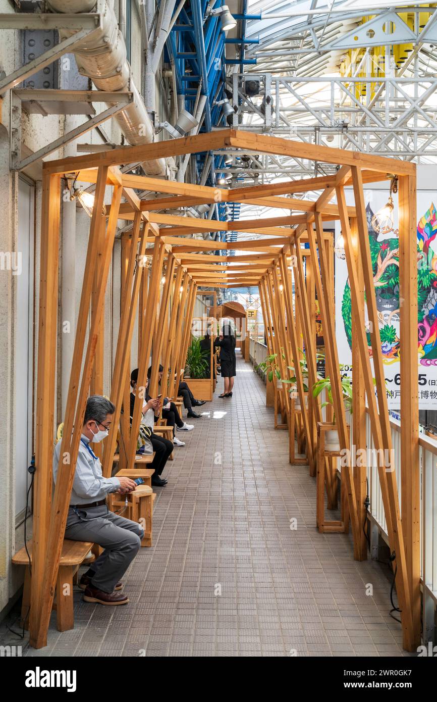 Kostenlose Nutzung von Sitzkabinen aus Holz vor einem Buchladen auf der zweiten Ebene des Kobe Gai Shopping Walkway in Sannomiya, Kobe in Japan. Stockfoto