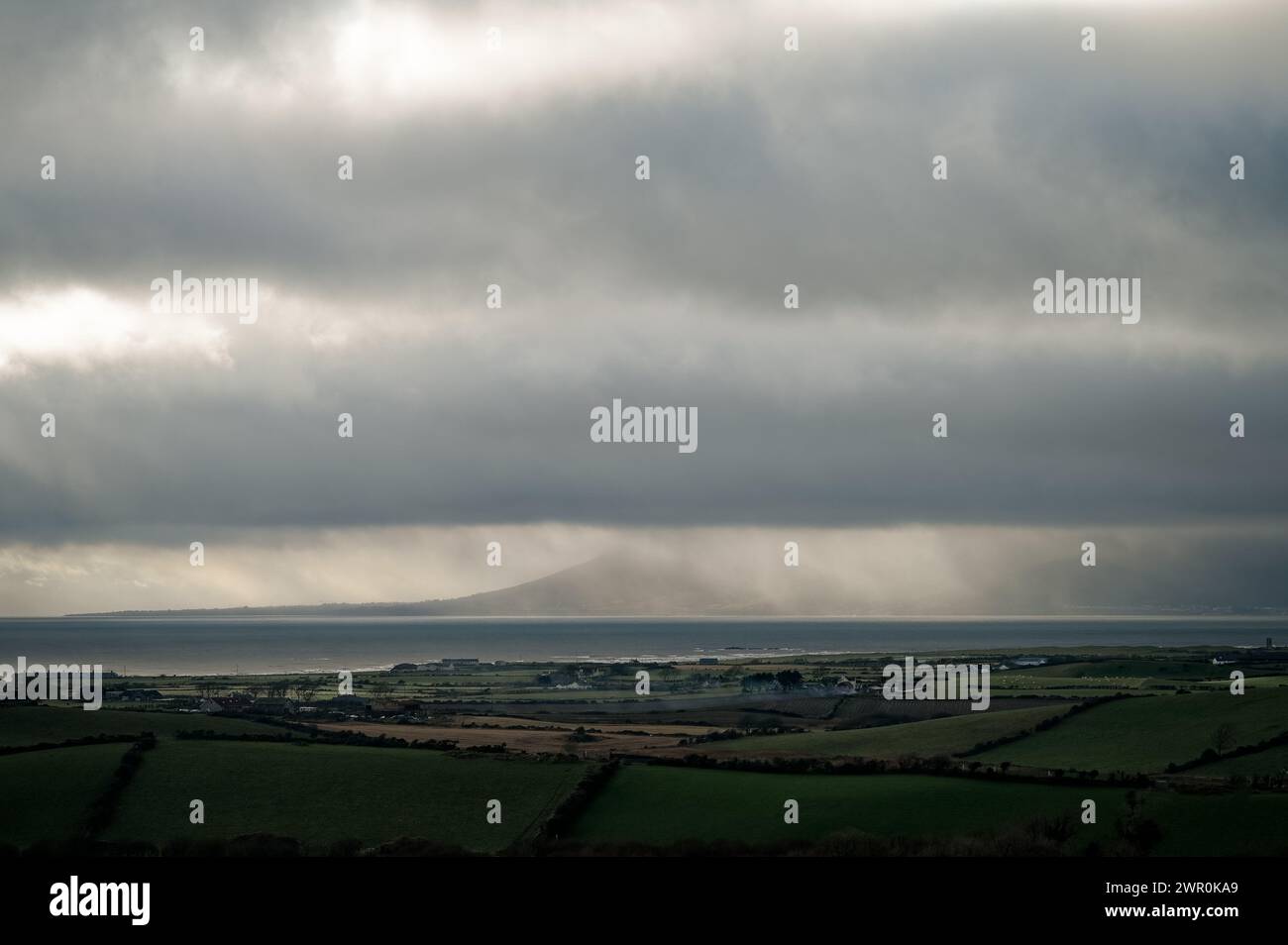 Blick über Dundrum Bay am nassen Winternachmittag; Newcastle und Mournes hinter Regenvorhang; Himmel mit grauen Wolkenbändern. Stockfoto