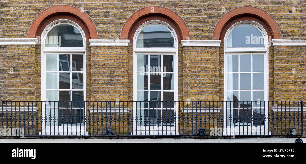 Balkon mit klassischen weißen Bogenfenstern in typischer londoner Architektur mit roter Backsteinmauer Stockfoto