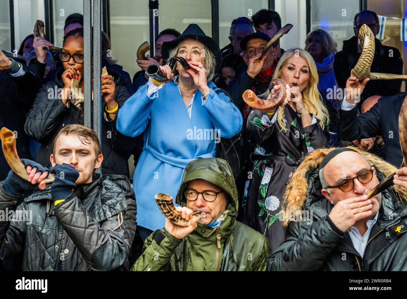 London, Großbritannien. März 2024. Maureen Lipman und Vanessa Feltz blasen ihre Hörner - Juden und Sympathisanten blasen Shofars (Widderhörner von spiritueller Bedeutung) und Pfeifen, angeführt von Vanessa Feltz, Mike Freer MP und Dame Maureen Lipman in einer Synagoge in der Nähe der Abbey Road in London. Die Absicht besteht darin, Solidarität mit den mehr als 100 Geiseln zu zeigen, die noch immer in Gaza festgehalten werden, und die Welt für die schrecklichen Bedingungen zu wecken, denen sie ausgesetzt sind. Der „Schlag“ wird 1,55 Minuten dauern, was die 155 Tage anbelangt, in denen sie in Gefangenschaft waren. Die Veranstaltung ist Teil der globalen Initiative „Blow for Geiseln“, die von Marcel Kno organisiert wird Stockfoto