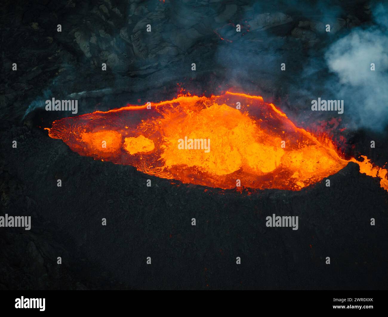 Fließende Lava, heißes Magma, das aus dem Vulkankrater fließt, Seitenansicht aus der Luft. Konzepte von Vulkanausbruch und isländischem Feuer- und Eisland. Stockfoto
