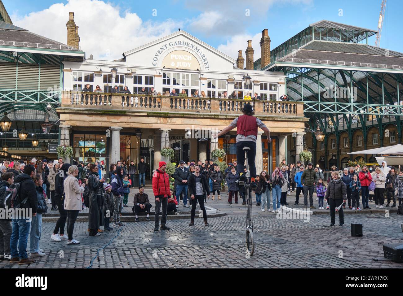 Straßenkünstler auf einem Einrad, der die Öffentlichkeit auf dem Covent Garden Market, London, Großbritannien, unterhält Stockfoto