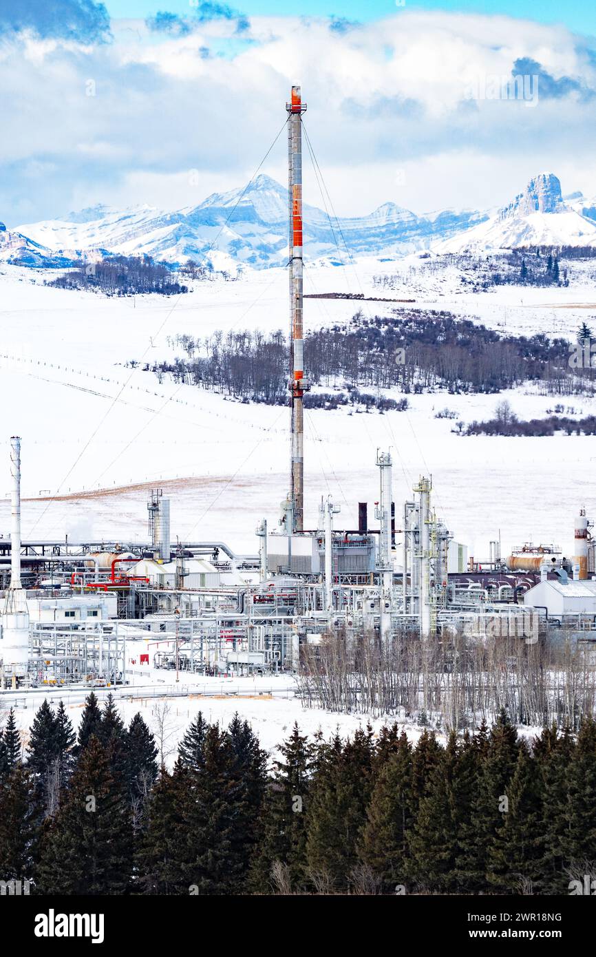 Wintergasanlage mit Flare-Stack mit Blick auf die kanadischen Rocky Mountains und schneebedeckte landwirtschaftliche Felder westlich von Cochrane Alberta Canada. Stockfoto