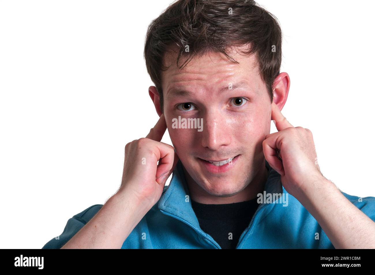 Kopfporträt eines jungen brünetten Kaukasiers, der seine Zeigefinger mit einem genervten Gesichtsausdruck in die Ohren steckt und auf die CA blickt Stockfoto