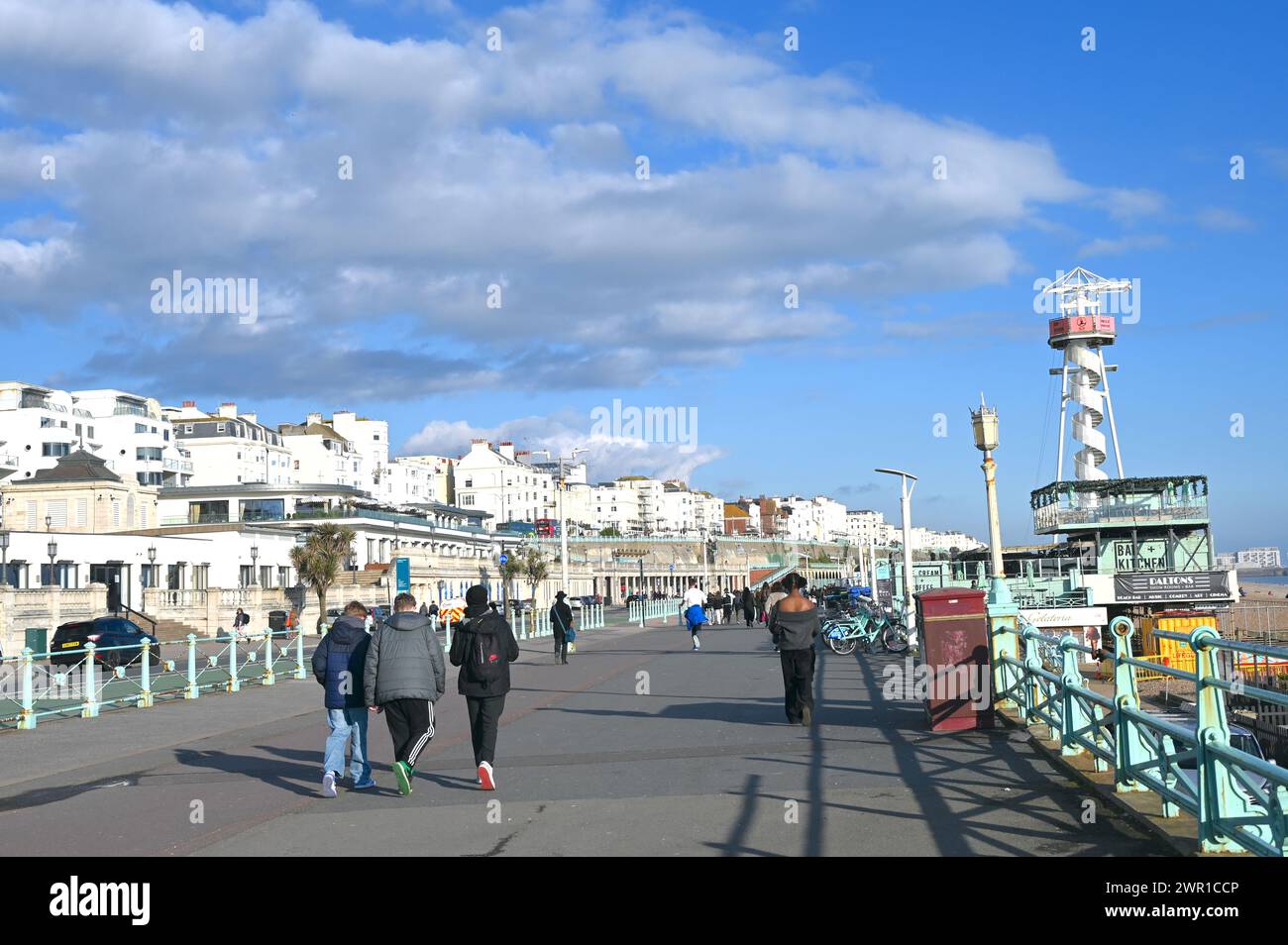 Junge Leute laufen an einem sonnigen Tag auf der Brighton Promenade. Stockfoto