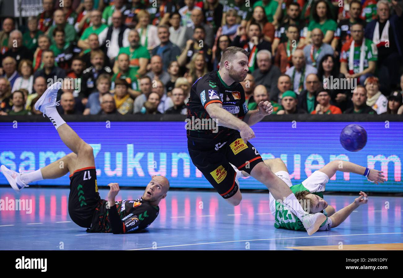 10. März 2024, Sachsen-Anhalt, Magdeburg: Handball, Bundesliga, SC Magdeburg - Füchse Berlin, Spieltag 25, GETEC Arena. Magdeburgs Lukas Mertens (Mitte) wirft auf das gegnerische Tor, während Magdeburgs Tim Hornke (links) und Berlins Mathias Gidsel auf dem Boden liegen. Foto: Ronny Hartmann/dpa Stockfoto