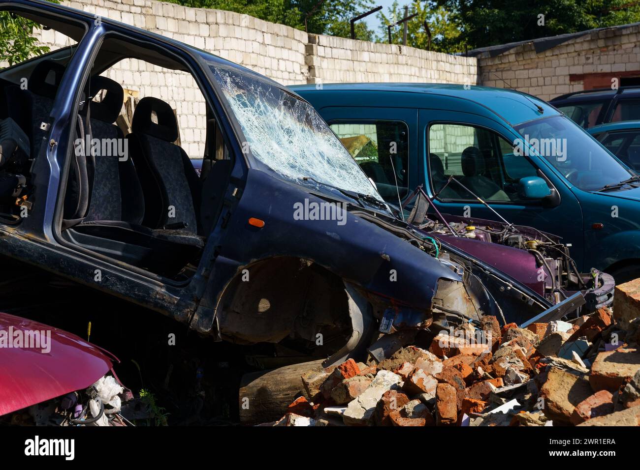 Ein Auto ist mit einem Schutthaufen kollidiert, was zu schweren Schäden am Fahrzeug und zu Trümmern führte, die sich um die Szene verstreut haben. Stockfoto